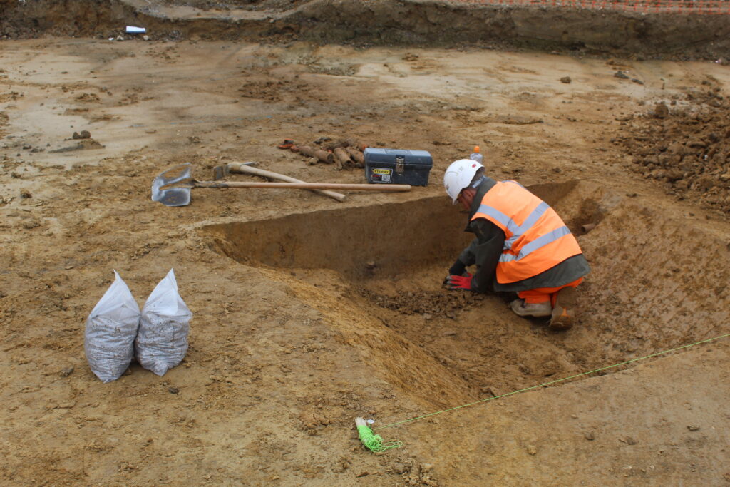 Archaeologist excavating a ditch slot